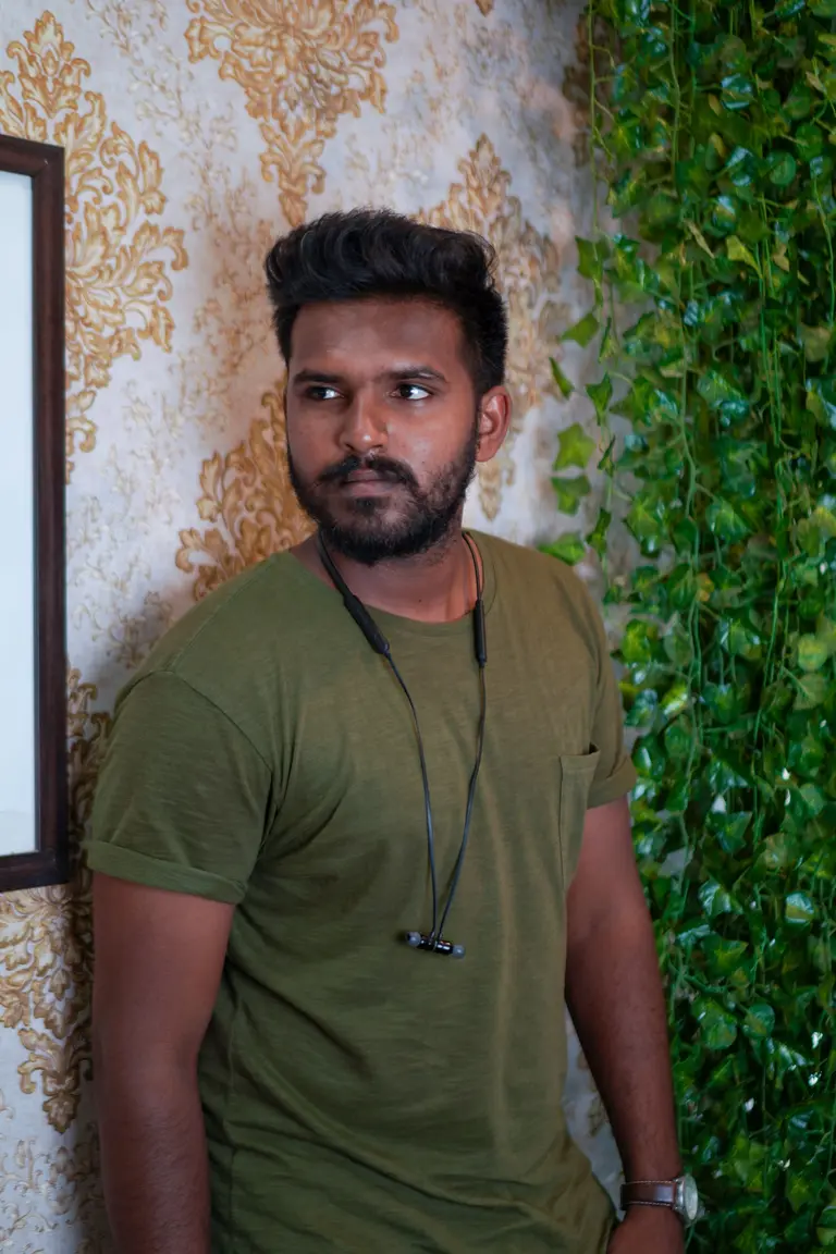 A bearded man in an olive shirt in front of patterned wallpaper, used as the fictional designer Aarav Sen (stock photo)