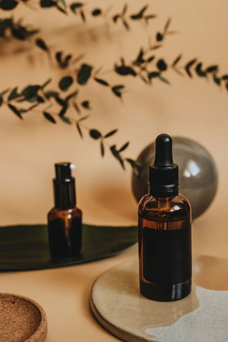 Two amber skincare bottles on a ceramic dish with eucalyptus branches, an example of packaging and brand identity