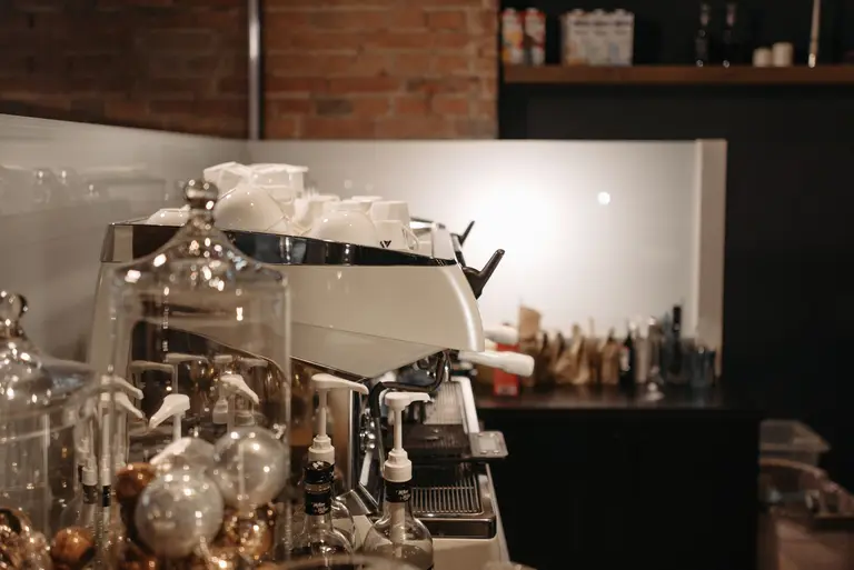 An espresso machine and glassware on a café counter