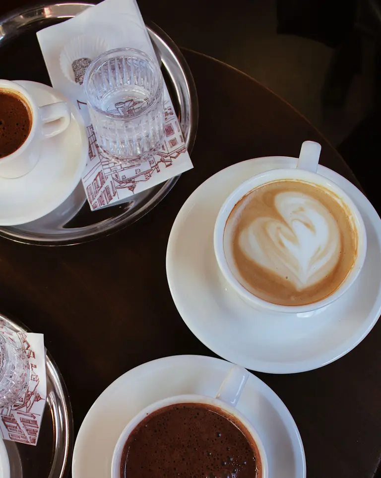 An overhead view of latte art and espresso cups on a café table