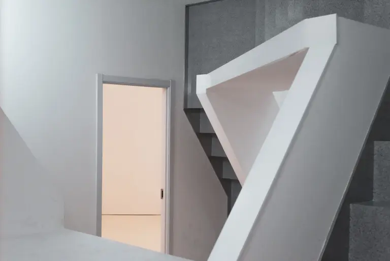 A white minimalist interior with a staircase and an open doorway