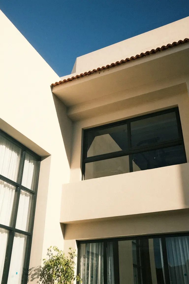 A modern house with large windows and a balcony against a blue sky, representing the Terra Estates website